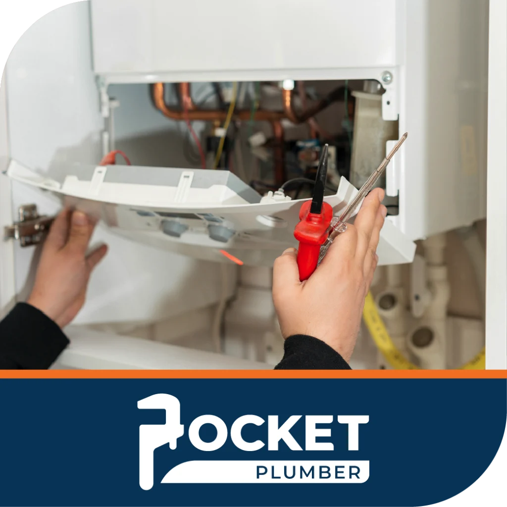 A person's hands use a tool to work on the internal components of an open white boiler or water heater, above the "Pocket Plumber" logo